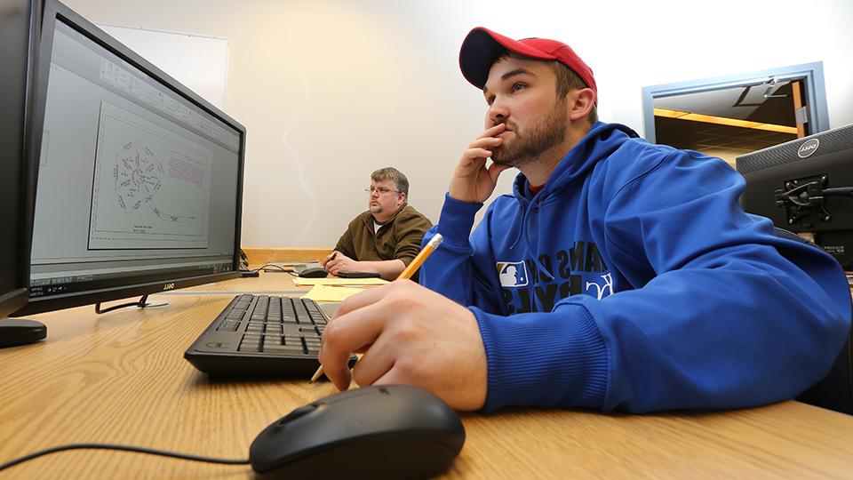 two students practicing AutoCAD on desktop computers