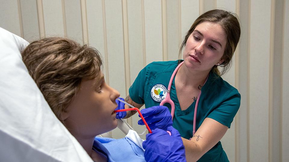 a nursing student works with a simulation dummy