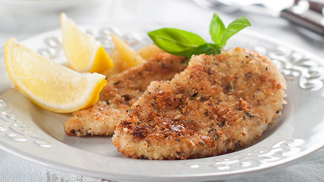 Breaded fish filet garnished with lemon wedges