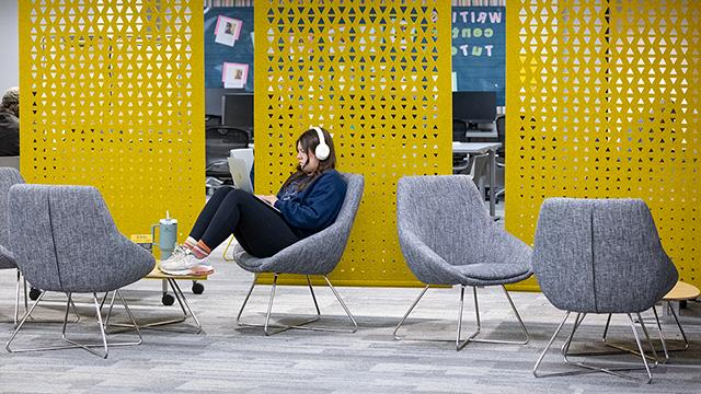 Student in a study space, wearing headphones, working on a laptop