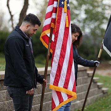 Veterans holding the American flag, heads bowed, as they listen to Taps